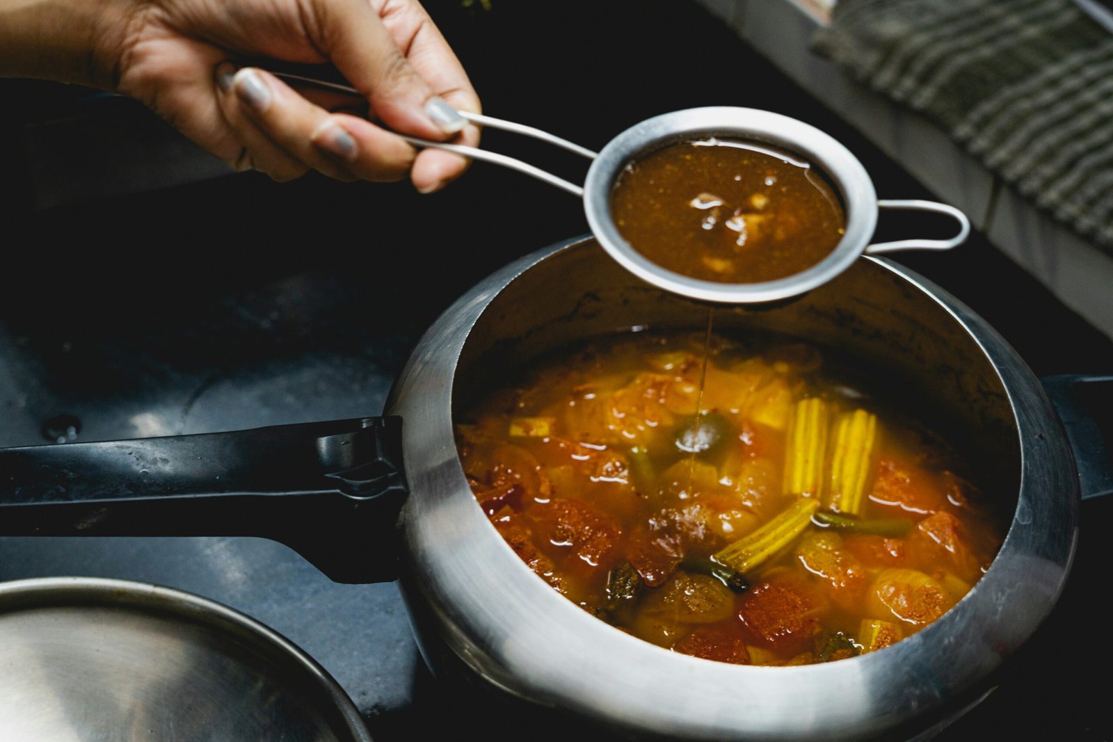 A person holding a spoon over a pot of soup